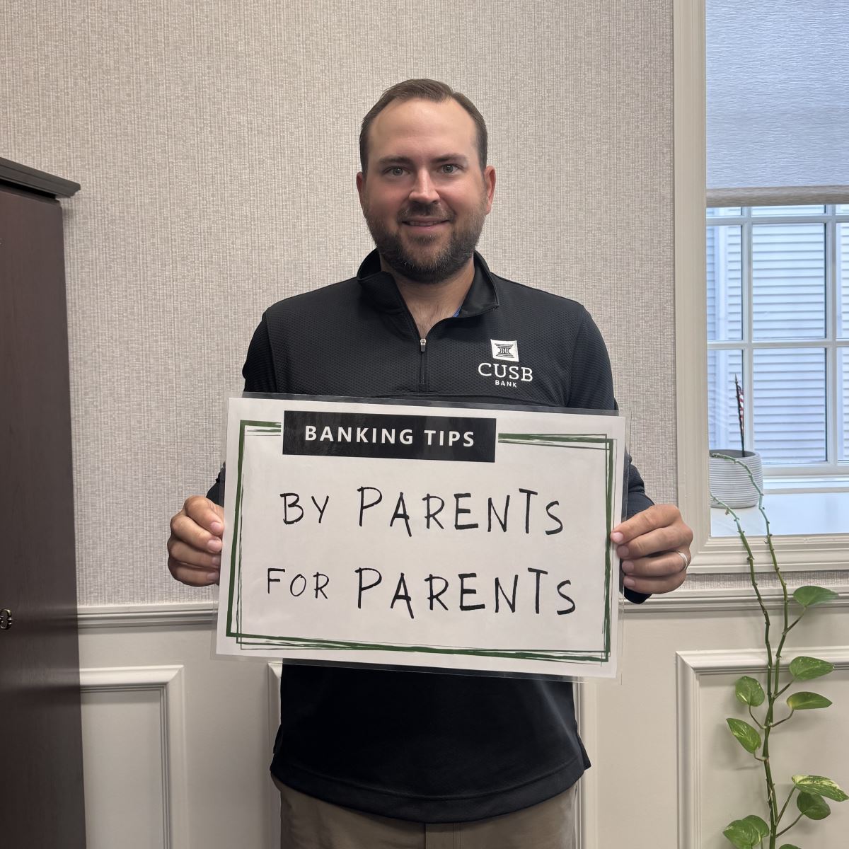 Drew holding up the Banking Tips: By Parents for Parents sign.